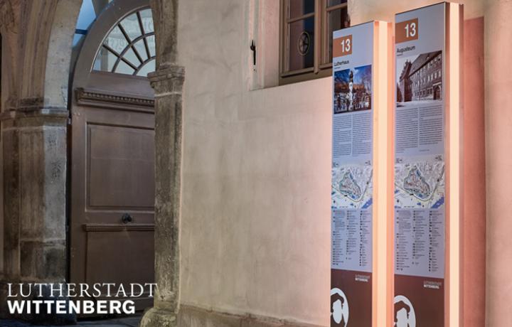 Beleuchtete Stelen des Innenstadtleitsystems Wittenberg. Sie wurden aus V4A-Edelstahl nach den grafischen Vorgaben des Büros Jo Schaller aus Halle vandalismussicher und barrierefrei beschriftet sowie fachgerecht in das denkmalgeschützte Umfeld integriert.